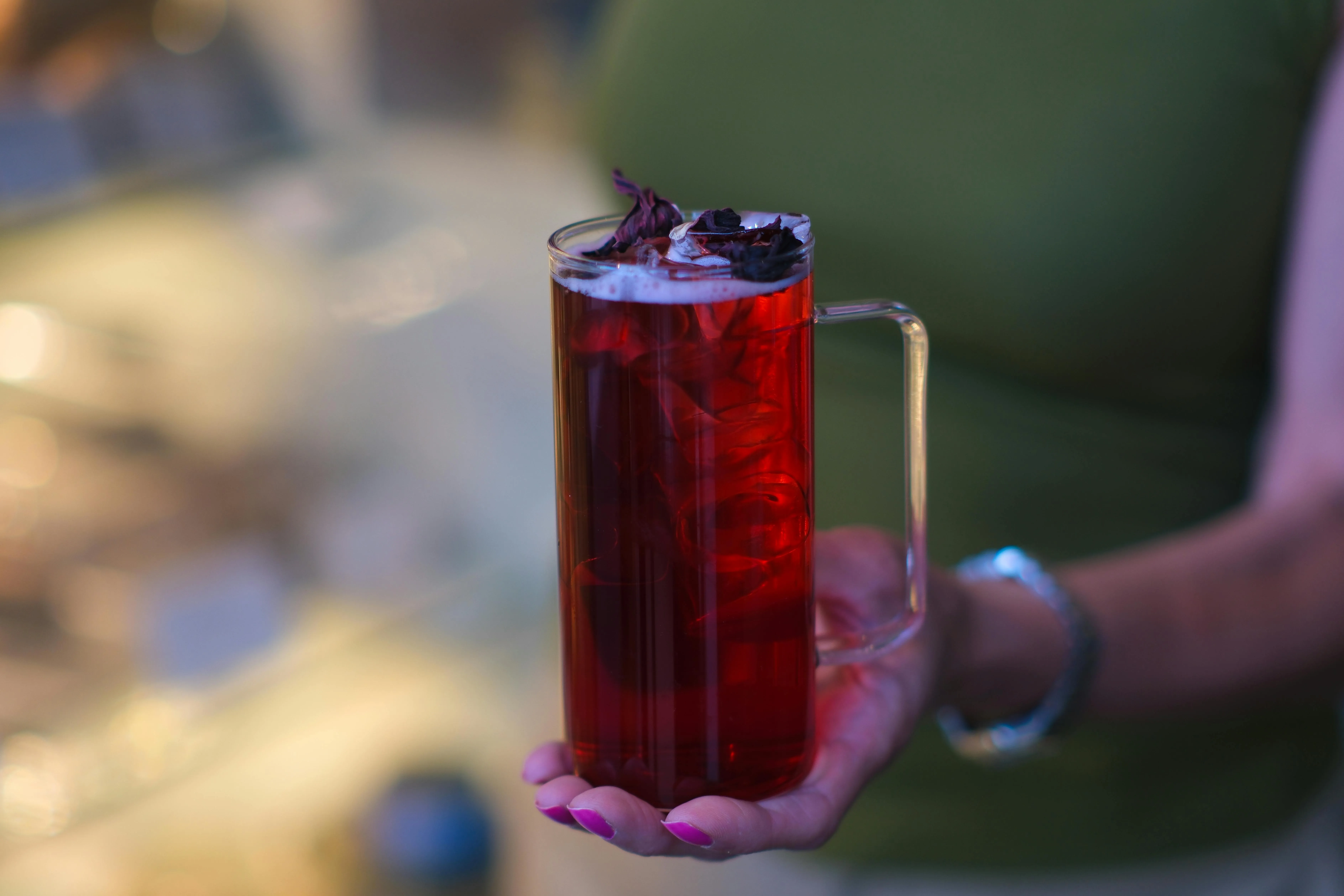 Glass of vibrant ruby-red hibiscus tea with dried hibiscus flowers